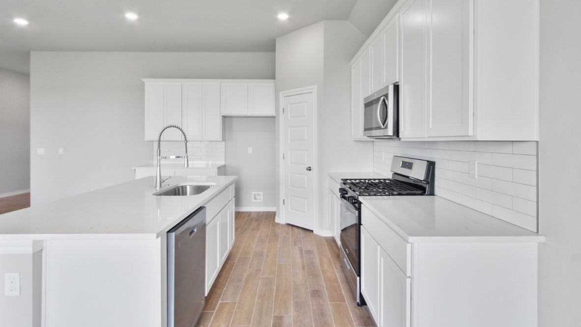 Bright and spacious kitchen with quartz countertops, stainless steel appliances, and an island with bar seating.