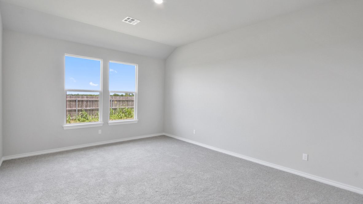 Primary bedroom with ceiling fan, plush carpeting, and a large walk-in closet.