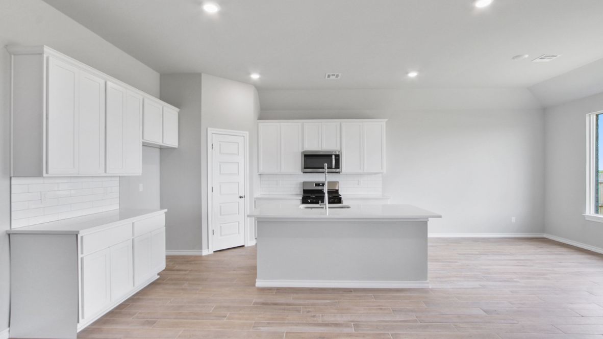 Bright and spacious kitchen with quartz countertops, stainless steel appliances, and an island with bar seating.