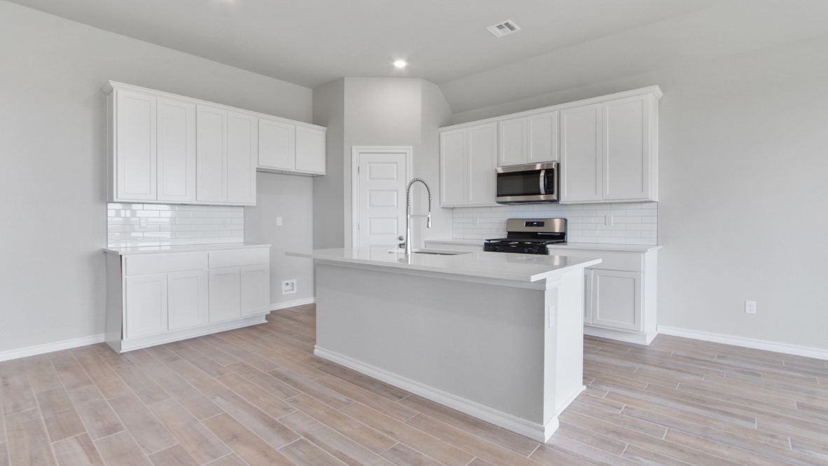 Bright and spacious kitchen with quartz countertops, stainless steel appliances, and an island with bar seating.