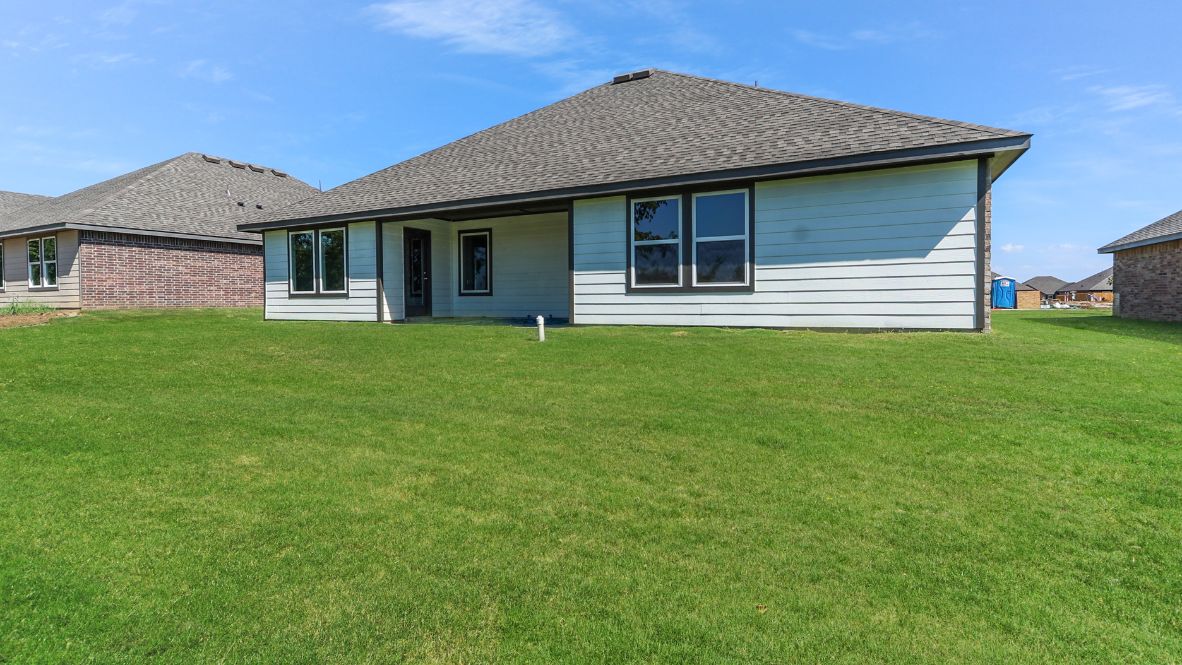 Outdoor covered patio with seating area overlooking a well-maintained lawn, perfect for relaxation.