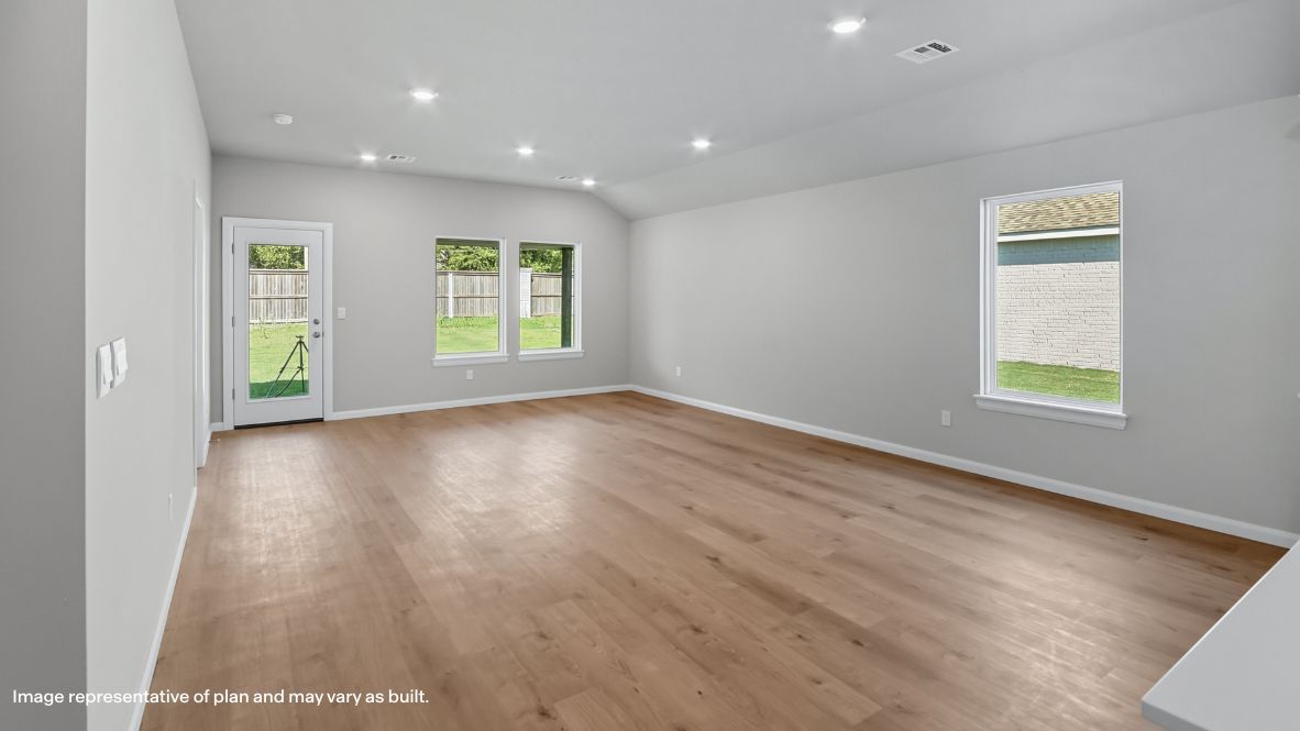 A cozy living room feature vinyl wood flooring and a view to the kitchen and dining area.