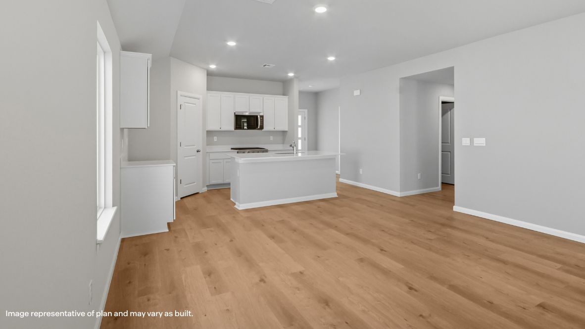A cozy living room feature vinyl wood flooring and a view to the kitchen and dining area.