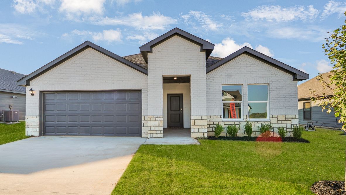 Newly built single story brick home with modern architecture, a double garage, and landscaped front yard.