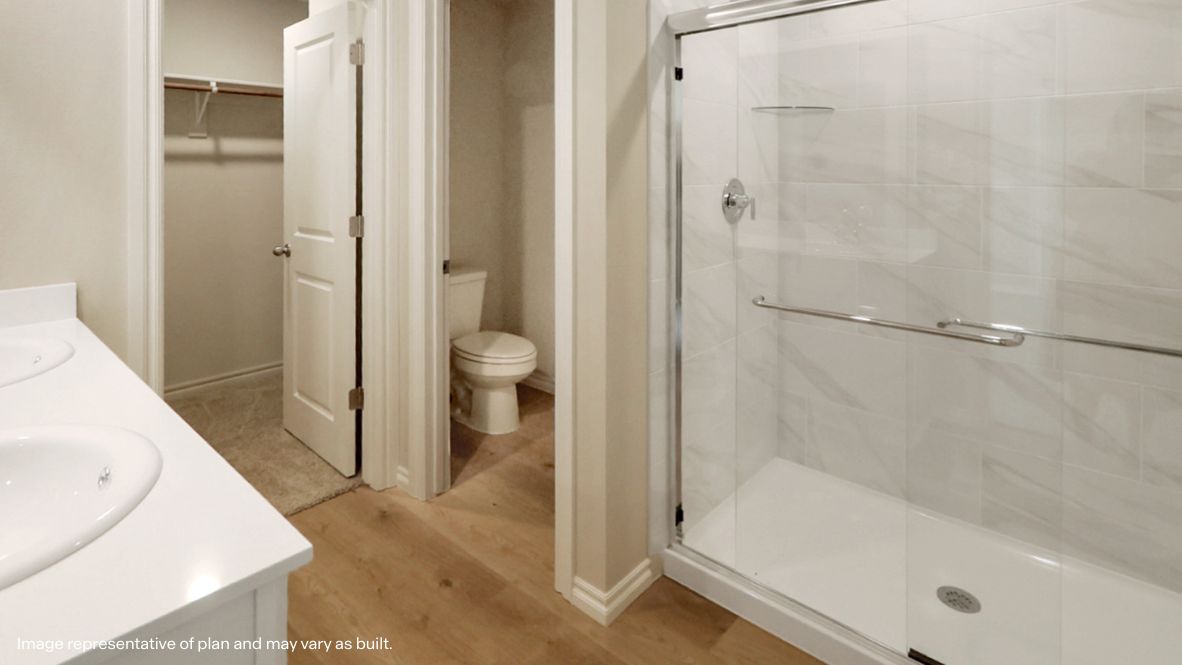 Owner’s ensuite featuring dual vanity sinks, stylish finishes, and walk-in closet access