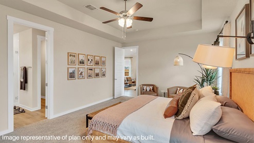 Primary bedroom with ceiling fan, plush carpeting, and a large walk-in closet.