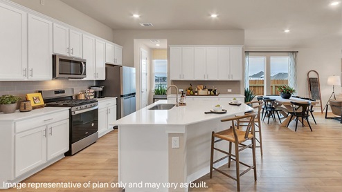 Bright and spacious kitchen with granite countertops, stainless steel appliances, and an island with bar seating.