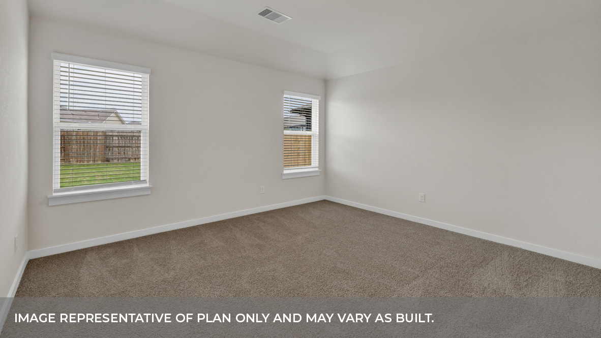 Primary bedroom with ceiling fan, plush carpeting, and a large walk-in closet.