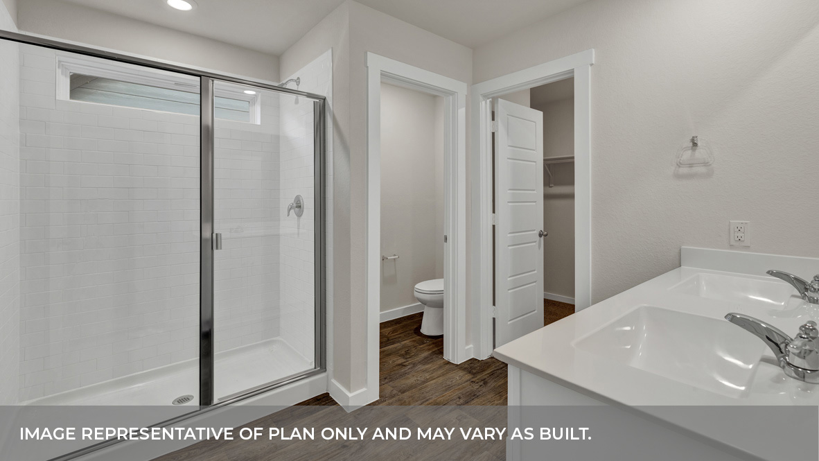Modern primary bathroom with double vanities, granite countertops, and a glass-enclosed shower with a walk-in closet.