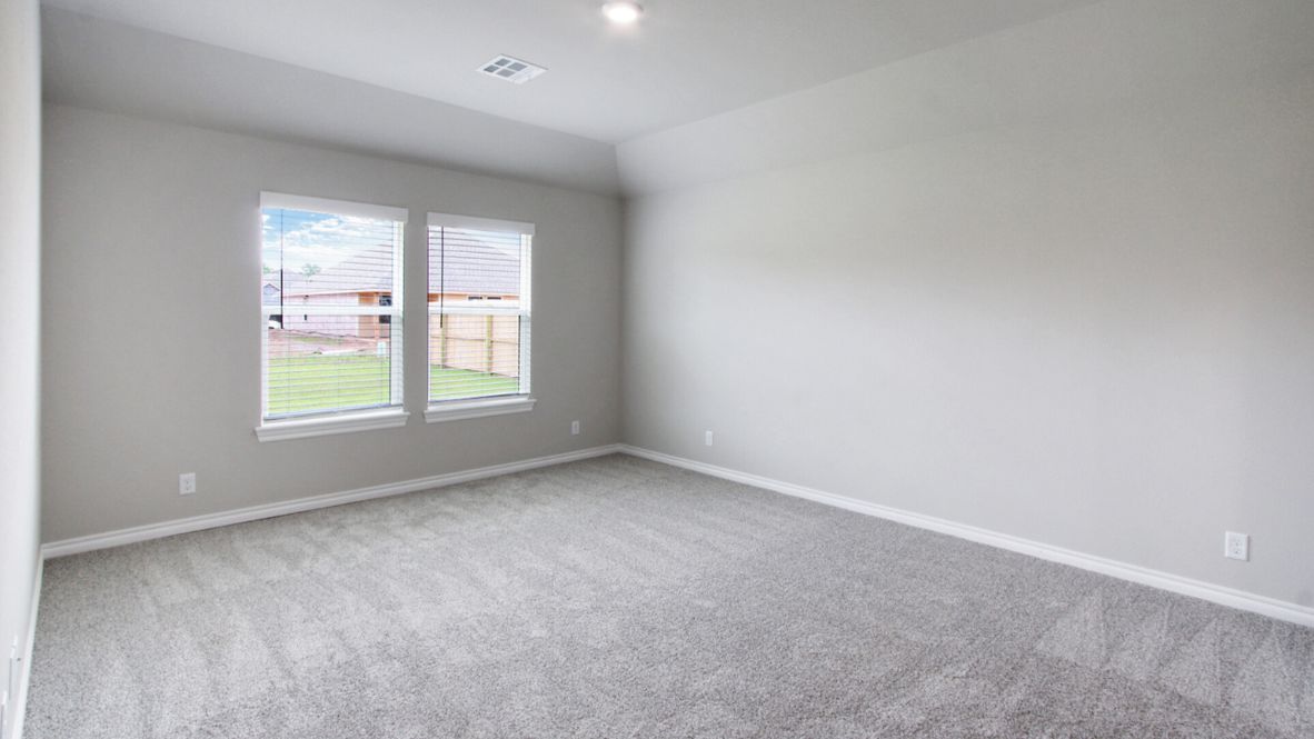 A spacious primary bedroom emphasizing open space and natural lighting.