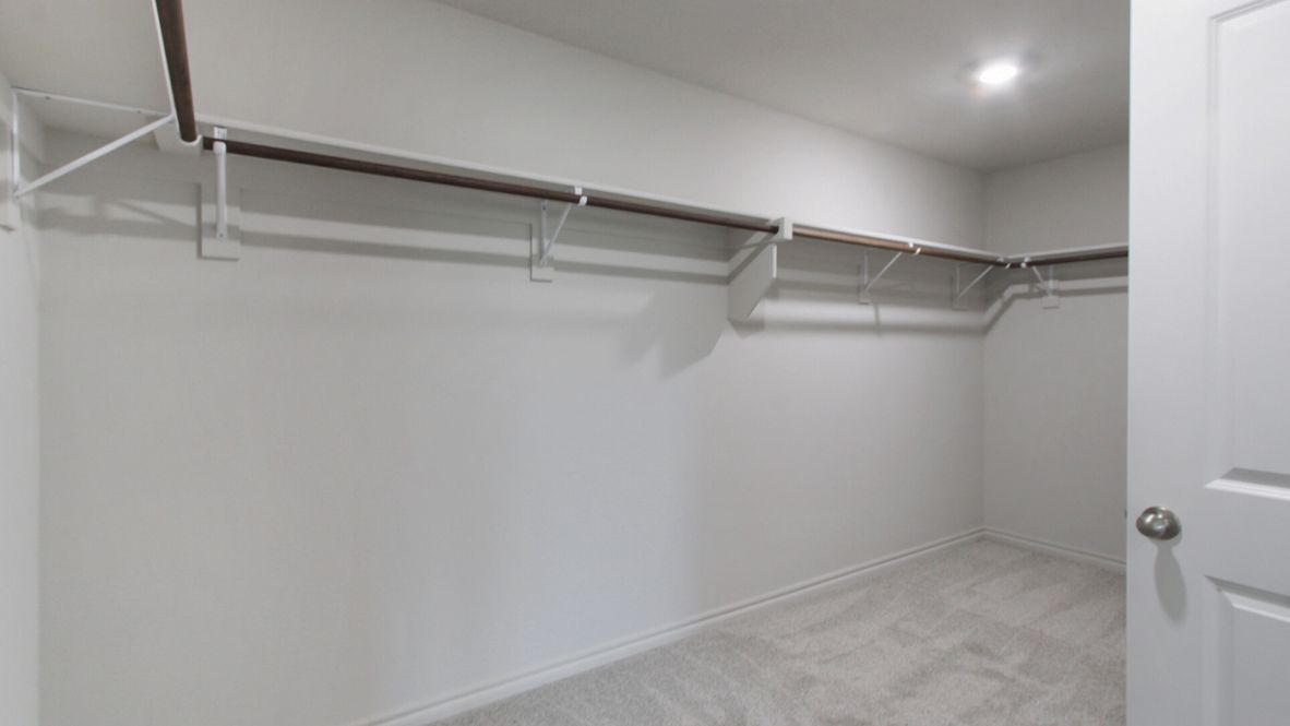 Modern primary bathroom with double vanities, granite countertops, and a glass-enclosed shower with a walk-in closet.