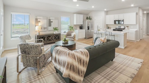 Interior of living room with large windows looking into kitchen