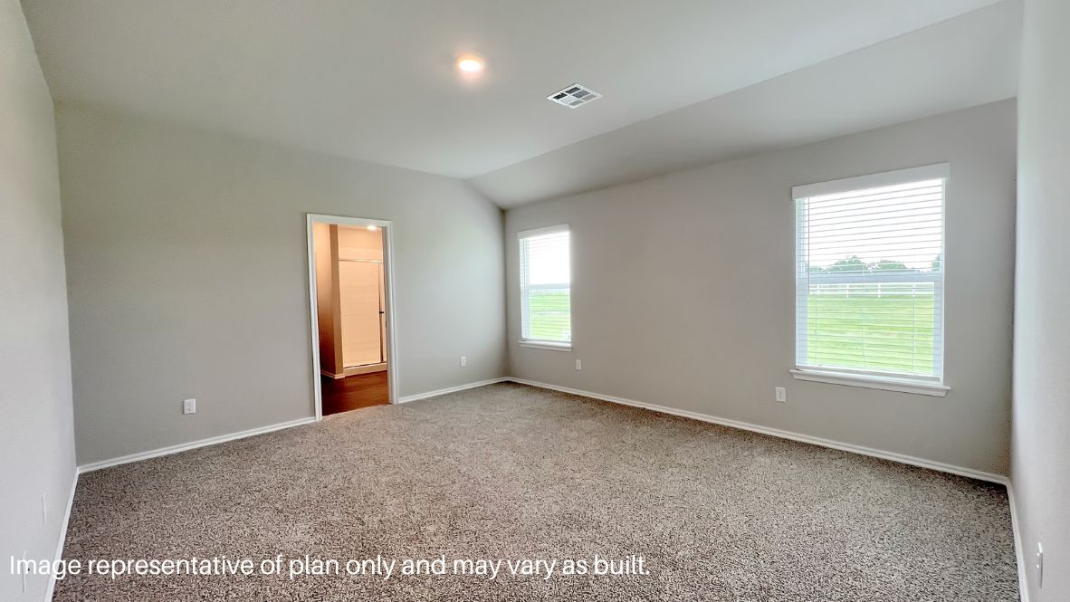 Primary bedroom with ceiling fan, plush carpeting, and a large walk-in closet.