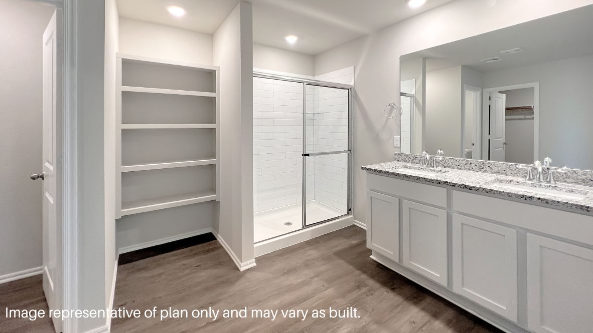 Modern primary bathroom with double vanities, quartz countertops, and a glass-enclosed shower with a walk-in closet.