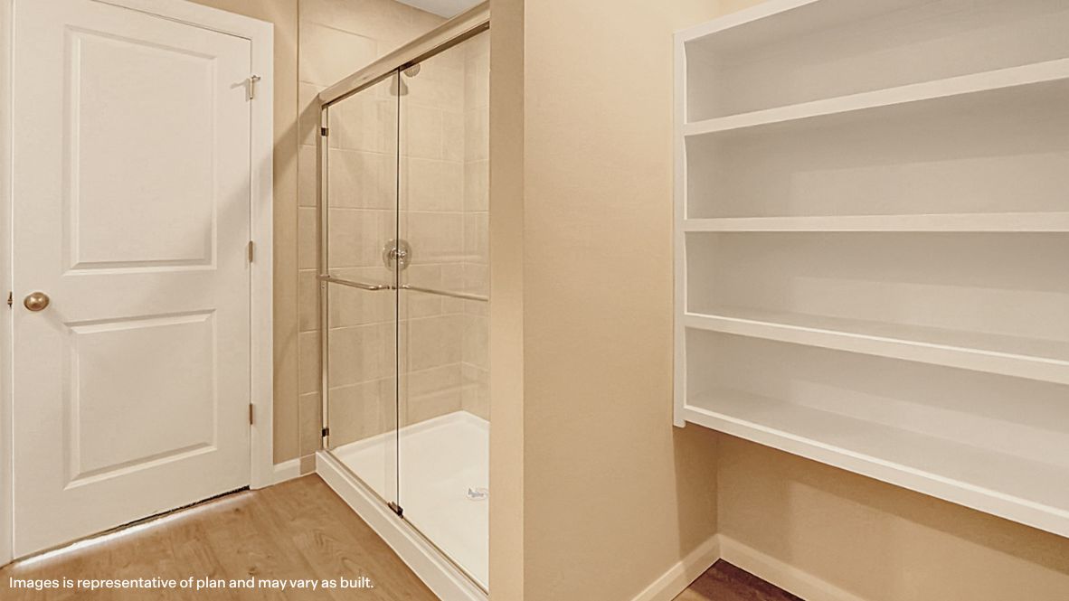 Modern primary bathroom with double vanities, quartz countertops, and a glass-enclosed shower with a walk-in closet.