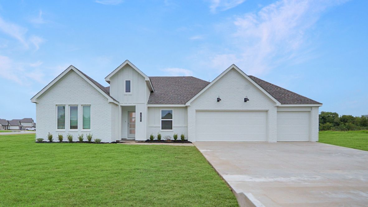 Newly built single story brick home with modern architecture, a double garage, and landscaped front yard.