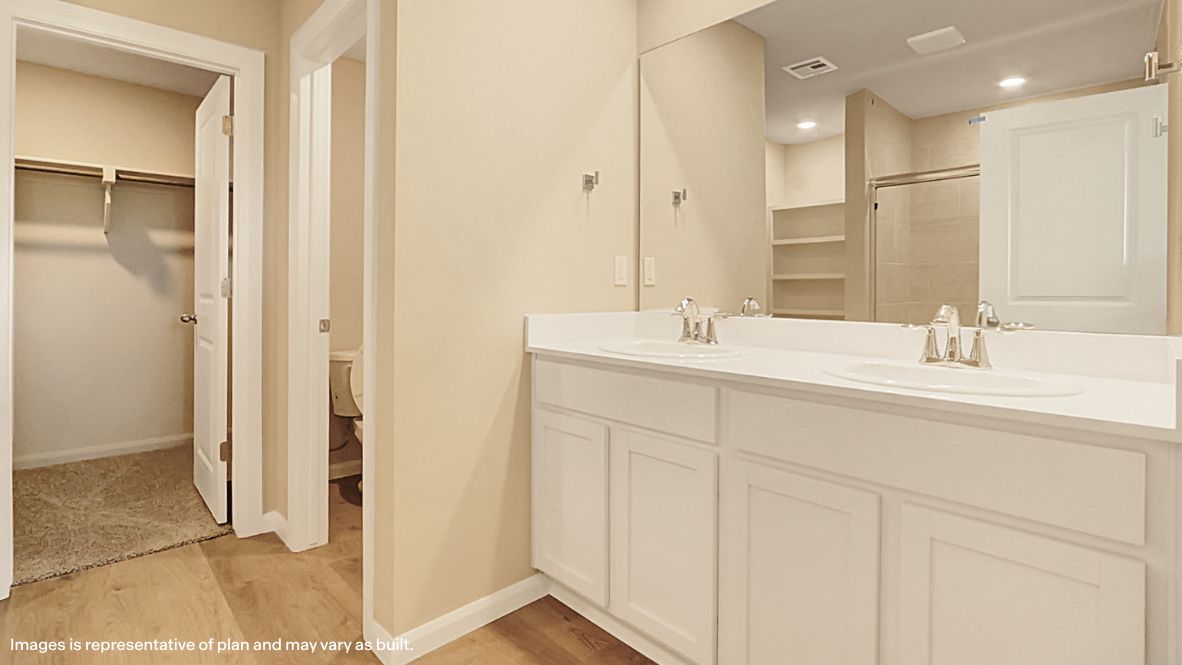 Modern primary bathroom with double vanities, quartz countertops, and a glass-enclosed shower with a walk-in closet.