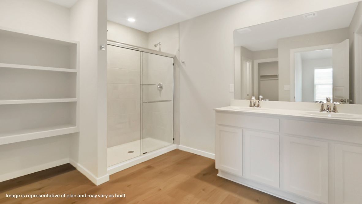 Modern primary bathroom with double vanities, quartz countertops, and a glass-enclosed shower with a walk-in closet.