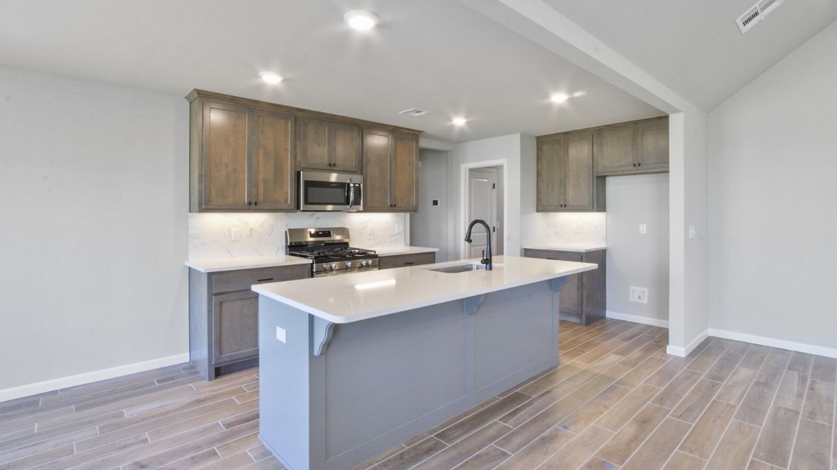 Bright and spacious kitchen with granite countertops, stainless steel appliances, and an island with bar seating.
