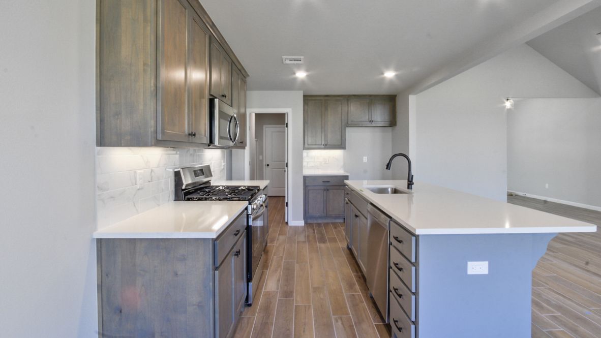 Bright and spacious kitchen with granite countertops, stainless steel appliances, and an island with bar seating.