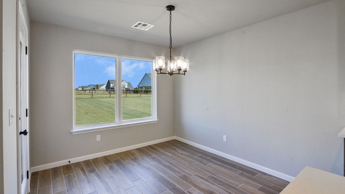 Spacious dining area with vinyl wood flooring, large window and tall ceiling.