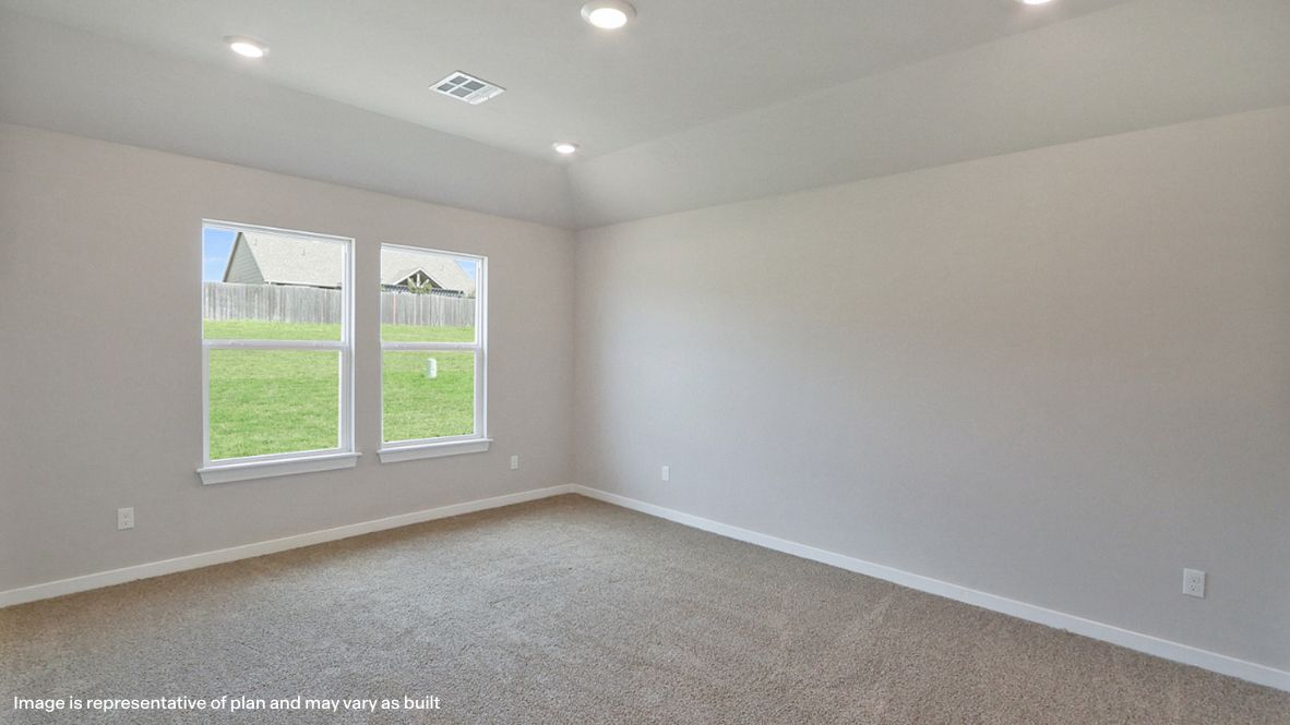 Primary bedroom with ceiling fan, plush carpeting, and a large walk-in closet.