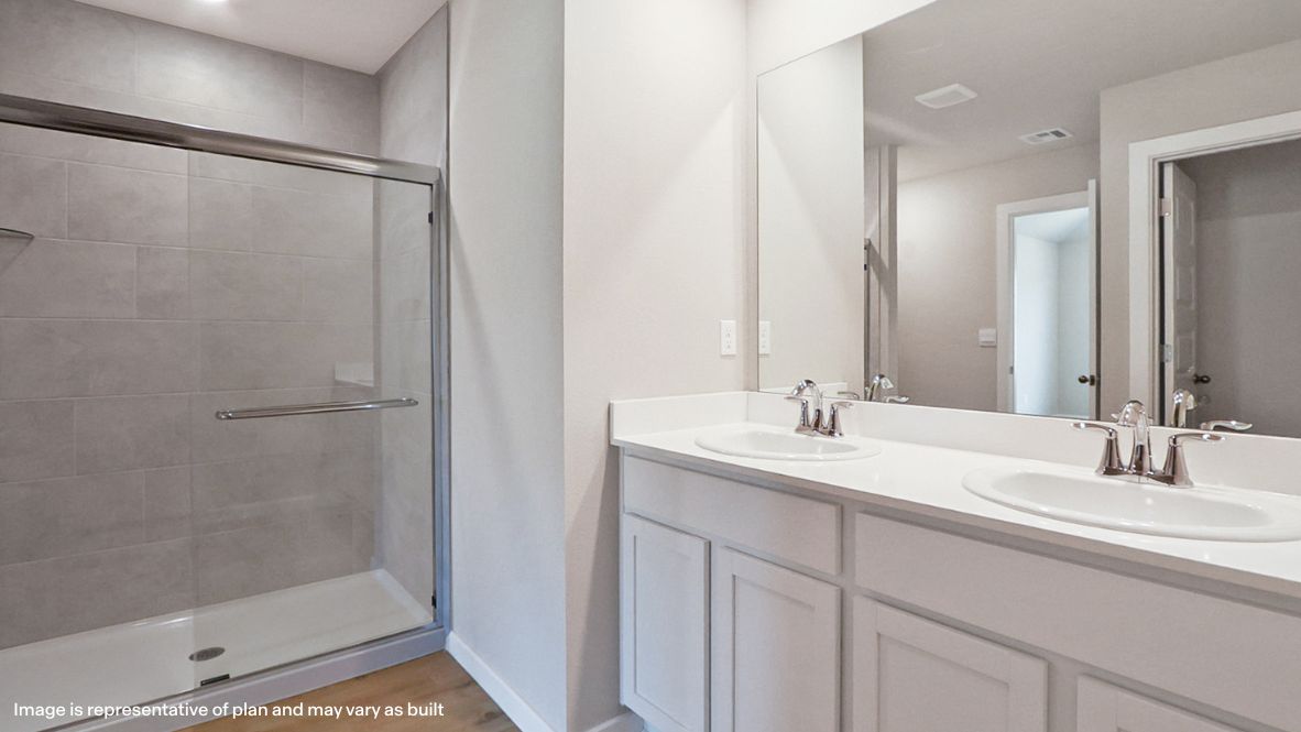 Modern primary bathroom with double vanities, quartz countertops, and a glass-enclosed shower with a walk-in closet.