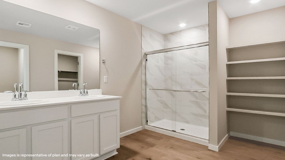 Modern primary bathroom with double vanities, quartz countertops, and a glass-enclosed shower with a walk-in closet.