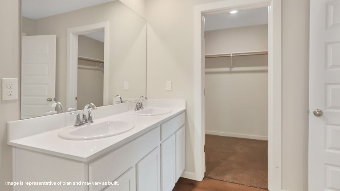 Modern primary bathroom with double vanities, quartz countertops, and a glass-enclosed shower with a walk-in closet.