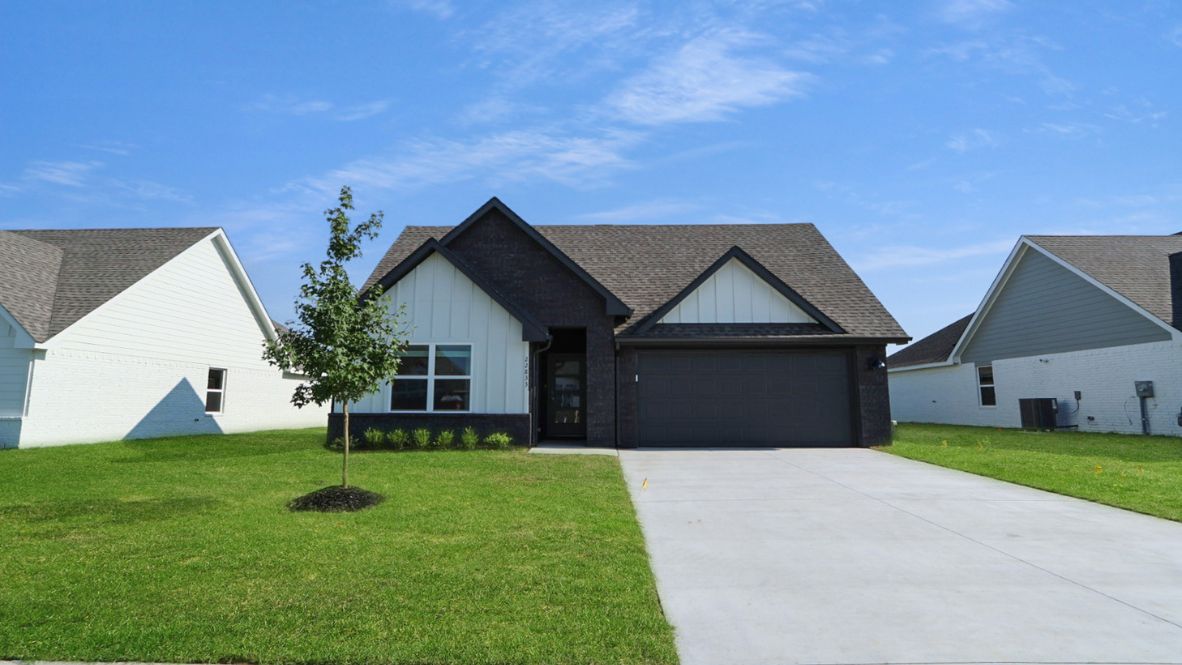 Street view showing dark garage door, driveway, and landscaped front yard