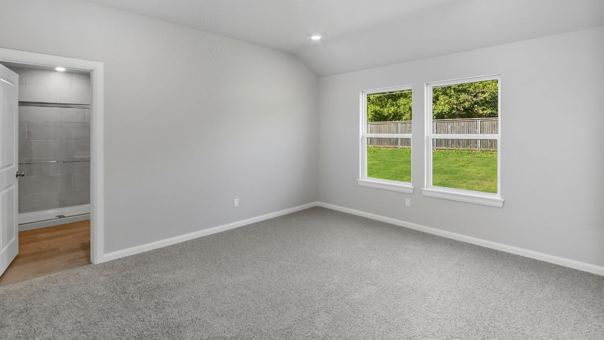 A spacious primary bedroom emphasizing open space and natural lighting.