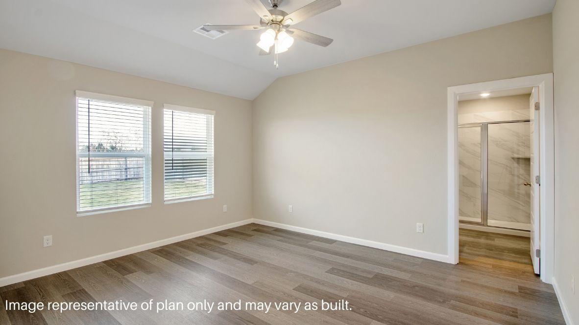 Primary bedroom with ceiling fan, plush carpeting, and a large walk-in closet.