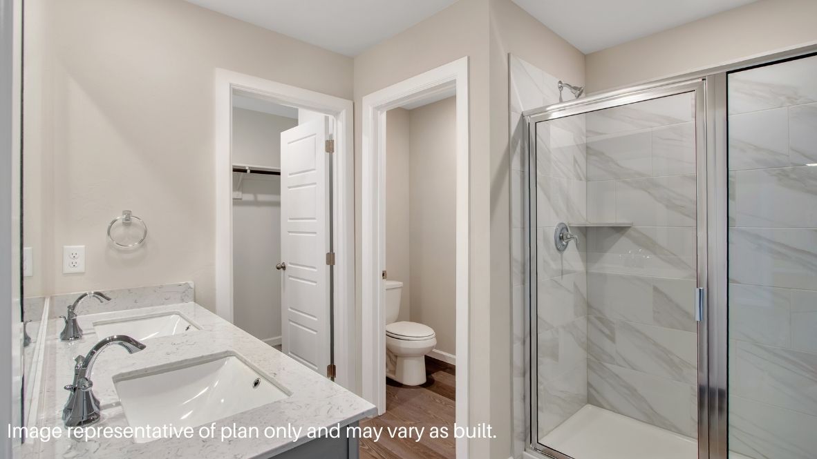 Modern primary bathroom with double vanities, quartz countertops, and a glass-enclosed shower with a walk-in closet.