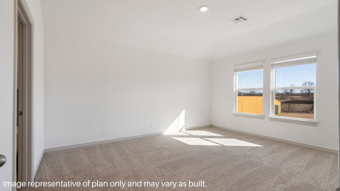 Primary bedroom with ceiling fan, plush carpeting, and a large walk-in closet.