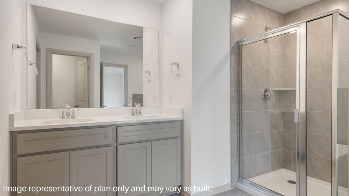 Modern primary bathroom with double vanities, quartz countertops, and a glass-enclosed shower with a walk-in closet.