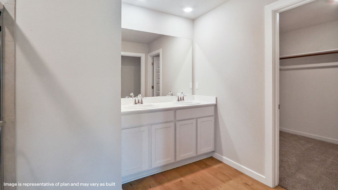 Modern primary bathroom with double vanities, quartz countertops, and a glass-enclosed shower with a walk-in closet.