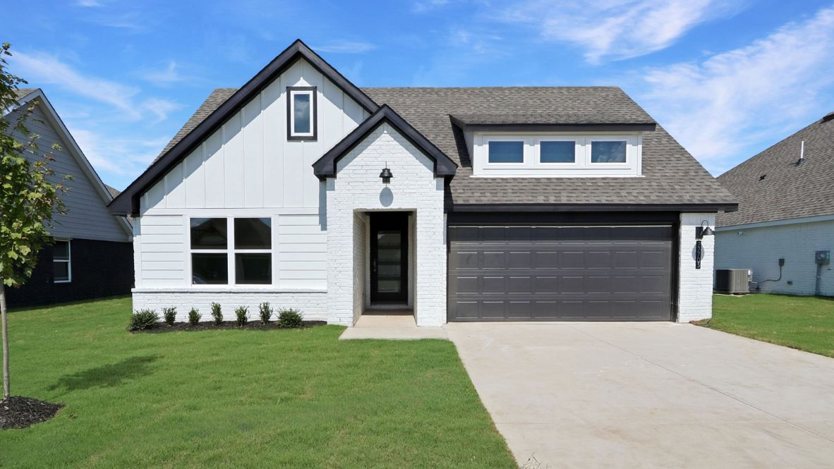 Modern single-story home with a brick exterior, two-car garage, and well-maintained front lawn in a suburban neighborhood.