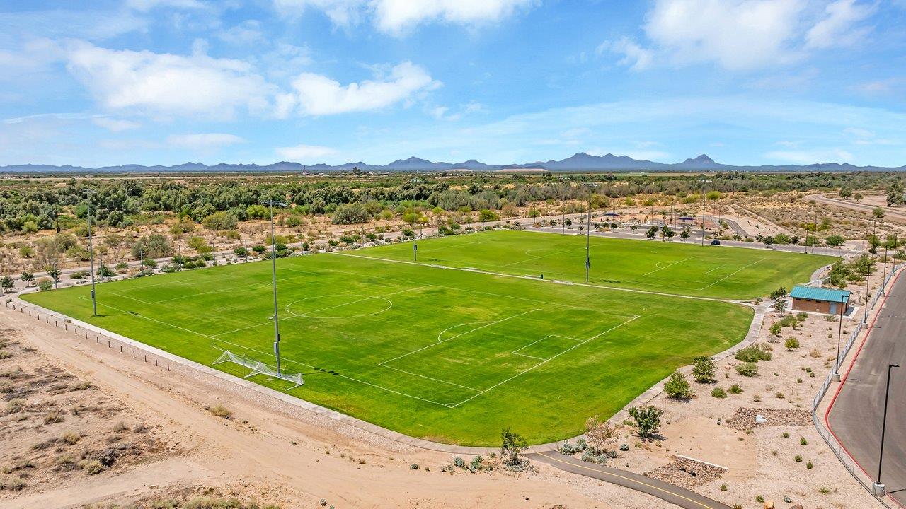 Welcome to The Kate at Coronet at Gladden Farms in Marana, Arizona – a spacious 2,227 sq. ft. two-story home designed to offer both luxury and practicality in a vibrant community setting.  As you step through the welcoming front porch, you’re greeted by an expansive entryway that leads into the heart of the home. The main floor features a generous great room that seamlessly flows into the dining area and kitchen, creating a perfect space for family gatherings and entertaining guests. The kitchen is a chef’s delight, boasting quartz countertops, a large island with a breakfast bar, modern appliances, and a walk-in pantry that provides ample storage.  The main floor also includes a convenient powder room for guests and direct access to the two-car garage, enhancing the home’s functionality. Just off the kitchen and dining room, a covered patio invites you to enjoy the beautiful Arizona weather, offering a serene spot for outdoor dining or relaxation.  Upstairs, the master suite offers a peaceful retreat, complete with a spacious bedroom, a large walk-in closet, and an en-suite bathroom featuring dual vanities and a walk-in shower. The upper level also includes three additional bedrooms, a full bathroom, and a centrally located utility room for added convenience. A versatile loft area provides additional living space, perfect for a playroom, home office, or secondary lounge.  The Kate in Coronet at Gladden Farms is designed with energy efficiency at its core. This DOE Zero Energy Ready Home features advanced energy-saving technologies such as tankless water heaters, energy-efficient LED lighting, and high-performance spray foam insulation, ensuring lower utility costs and a reduced environmental footprint.  Living at Coronet at Gladden Farms means more than just having a beautiful home. Residents enjoy access to 830 acres of green space, 28 parks, 19 playgrounds, and exclusive amenities like a sparkling community pool, fitness center, and clubhouse. The gated community also offers walking trails, a dog park, and close proximity to everyday conveniences, making it an ideal environment for families and active lifestyles.