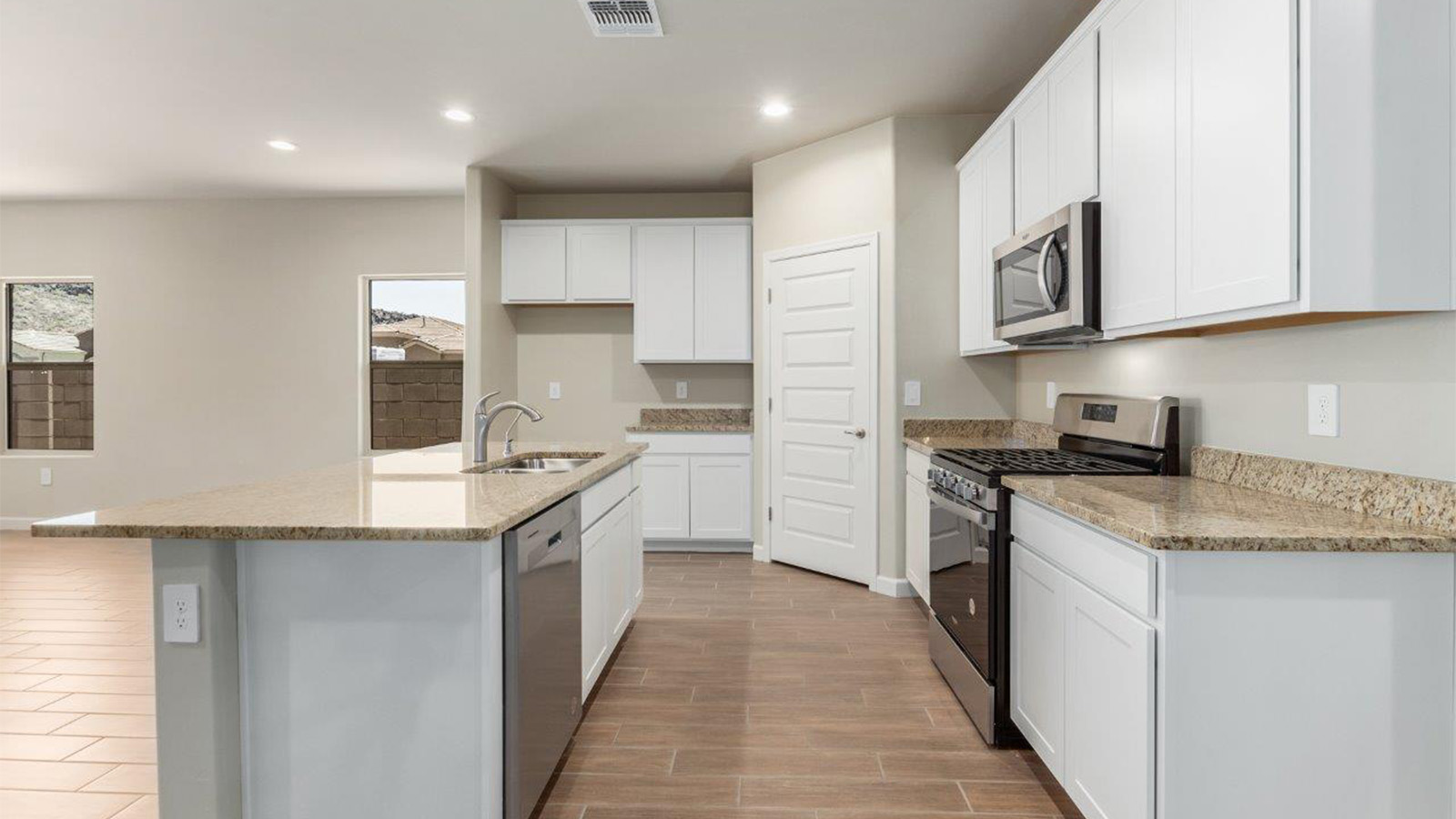 The Lakeway, situated within the beautiful Sycamore Vista community in Vail, Arizona, offers a perfect blend of functionality and comfort, ideal for both growing families and those who appreciate spacious living. With its 2,034 square feet of living space, this single-story new home features five bedrooms and three bathrooms, all meticulously designed to maximize space and convenience.  Entering The Lakeway offers a bright and airy atmosphere that flows through the open-concept floor plan. The heart of the home is the great room, seamlessly connected to the kitchen and dining area. The kitchen is equipped with quartz countertops, Shaker-style cabinetry, and a large island that serves as a focal point for both meal preparation and casual gatherings. The adjoining dining room provides a cozy space for family meals, with easy access to the covered patio through sliding glass doors, creating a wonderful indoor-outdoor living experience.  The primary bedroom is a true retreat, offering a spacious walk-in closet and an en-suite bathroom with a dual-sink vanity and an elegant, tiled shower. The additional bedrooms are thoughtfully spaced to provide ample privacy for family members or guests, and the two secondary bathrooms are finished with modern fixtures and plenty of storage. This home offers a 2-3 car garage option for substantial space of vehicles and storage, accommodating the practical needs of busy households.  Standard features in The Lakeway at Sycamore Vista include energy-efficient elements like a tankless water heater, spray foam insulation, and LED lighting throughout. The home also comes with a Home is Connected® Smart Home package, which includes a smart thermostat, video doorbell, keyless entry, and more, ensuring modern conveniences are at your fingertips. The front yard is beautifully landscaped and includes an auto drip irrigation system, enhancing the curb appeal of this stunning home.  Nestled within Sycamore Vista, The Lakeway combines the tranquility of a rural setting with proximity to excellent schools, shopping, dining, and outdoor recreation, making it an exceptional place to call home.