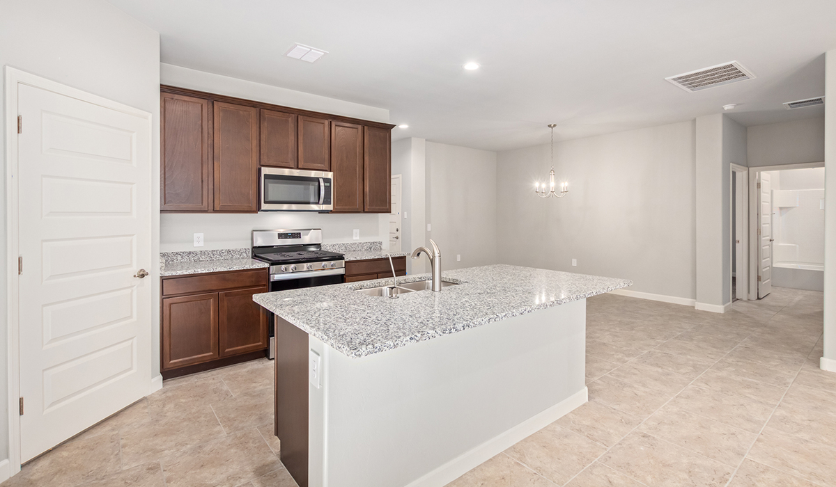 The Lakeway, situated within the beautiful Sycamore Vista community in Vail, Arizona, offers a perfect blend of functionality and comfort, ideal for both growing families and those who appreciate spacious living. With its 2,034 square feet of living space, this single-story new home features five bedrooms and three bathrooms, all meticulously designed to maximize space and convenience.  Entering The Lakeway, you’ll immediately notice the bright and airy atmosphere that flows through the open-concept floor plan. The heart of the home is the great room, seamlessly connected to the kitchen and dining area. The kitchen is equipped with quartz countertops, Shaker-style cabinetry, and a large island that serves as a focal point for both meal preparation and casual gatherings.  The primary bedroom is a true retreat, offering a spacious walk-in closet and an en-suite bathroom. The additional bedrooms are thoughtfully spaced to provide ample privacy for family members or guests, and the two secondary bathrooms are finished with modern fixtures and plenty of storage. This home offers a three-car garage option for substantial space of vehicles and storage, accommodating the practical needs of busy households.  Standard features in The Lakeway at Sycamore Vista include energy-efficient elements like a tankless water heater, spray foam insulation, and LED lighting throughout. The home also comes with a Home is Connected® Smart Home package, which includes a smart thermostat, video doorbell, keyless entry, and more, ensuring modern conveniences are at your fingertips. The front yard is beautifully landscaped and includes an auto drip irrigation system, enhancing the curb appeal of this stunning home.  Nestled within Sycamore Vista, The Lakeway combines the tranquility of a rural setting with proximity to excellent schools, shopping, dining, and outdoor recreation, making it an exceptional place to call home.  *Images shown are for reference only. They depict the model home and may not represent the actual home.