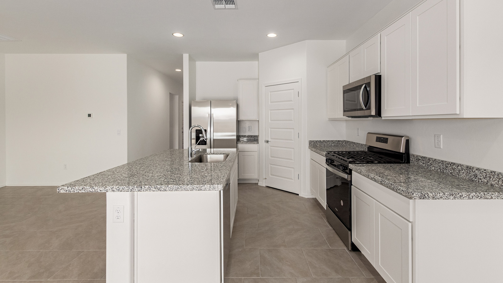 Discover The Easton at Saguaro Bloom in Marana, Arizona – a spacious 1,697 sq. ft. single-story new home designed to offer both style and functionality for today’s modern family.  As you enter through the front porch, you’re welcomed into a thoughtful layout that makes every square foot count. Near the front entrance is the first bedroom intentionally situated. This room can be utilized as a guest room, home office, or a cozy retreat.  Continuing down the hall you're welcomed into the great room, which flows seamlessly into the dining area and kitchen. This open-concept design ensures that the heart of the home is always connected. The kitchen is a culinary dream, featuring quartz countertops, a spacious island with a breakfast bar, and a walk-in pantry.  The great room opens up to a covered patio, an ideal space to unwind and enjoy beautiful desert sunsets. Whether you’re hosting a weekend barbecue or enjoying a quiet evening outdoors, this patio extends your living space into the scenic surroundings of Saguaro Bloom.  Just off the great room, a private hallway leads to the primary suite. The primary suite is generously sized and features a large walk-in closet, en-suite bathroom with walk-in shower, offering both privacy and convenience.  The Easton also features two additional bedrooms, well-positioned to share a full bathroom. These rooms are ideal for family members.  The Easton is designed with energy efficiency in mind and is DOE Zero Energy Ready Home Certified. This home includes a Connected® Smart Home package, featuring a smart thermostat, video doorbell, keyless entry, and Wi-Fi-enabled garage door opener. Energy efficiency is a cornerstone of the design, with features like spray foam insulation, and tankless water heater, offering long-term savings and sustainability.  Saguaro Bloom isn’t just a place to live, it’s a vibrant community with a wealth of amenities, from scenic walking trails to pools and playgrounds, ensuring that there’s always something for everyone.