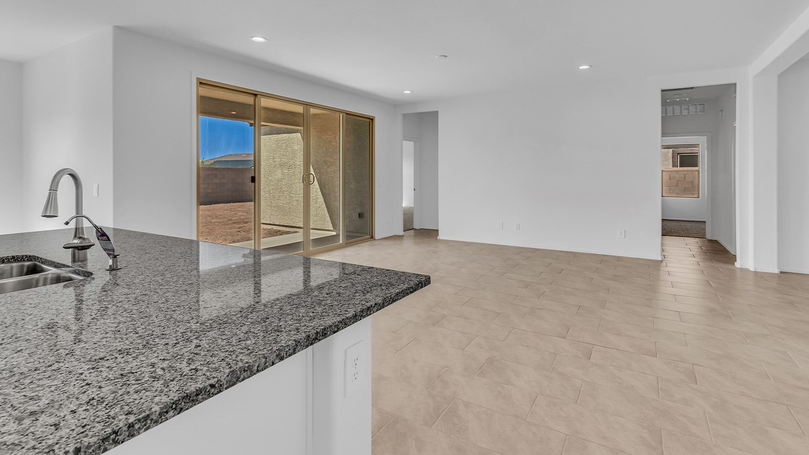 Welcome to The Pearl, a beautifully designed single-story new home located in the serene Cholla Ridge neighborhood of Saguaro Bloom. Spanning 2,431 square feet, this home offers four spacious bedrooms and three full bathrooms, making it an ideal choice for families who value both space and comfort.  As you enter through the front porch, you’re welcomed into a bright and open entryway that leads to the heart of the home. The expansive great room, dining area, and kitchen are seamlessly connected, providing a perfect setting for both everyday living and entertaining. The kitchen is a chef’s delight, featuring a large island, granite countertops, and Shaker-style cabinetry in double espresso. With a generously sized pantry and modern stainless steel gas appliances, this kitchen is both functional and stylish.  The Pearl’s layout includes a well-placed primary bedroom at the rear of the home, ensuring privacy and tranquility. The primary suite features a spacious walk-in closet and an en-suite bathroom with dual executive-height vanities and a large walk-in shower. The additional three bedrooms are located towards the front and sides of the home, each offering ample closet space and access to two full bathrooms, making this layout perfect for families and guests alike.  The outdoor living space is just as inviting, with a covered patio that extends from the great room, providing an ideal spot for enjoying Arizona’s beautiful weather. Whether you’re hosting a gathering or simply relaxing with a good book, this space is designed for your enjoyment.  The Pearl also features a dedicated utility room near the kitchen, making household tasks more convenient. A two-car garage offers plenty of space for vehicles and additional storage.  Built with energy efficiency and modern living in mind, The Pearl incorporates eco-friendly features and smart home technology, ensuring a comfortable and sustainable lifestyle. Large windows throughout the home allow natural light to flood the space, creating a warm and inviting atmosphere.  Located within the exclusive Cholla Ridge neighborhood at Saguaro Bloom, residents of The Pearl enjoy a range of amenities, including beautiful 12x24” tile flooring, and gourmet kitchens in select homes, all on lots with no rear neighbors. The community offers access to two pools, walking trails, and parks, all set against the stunning backdrop of the Tucson Mountains.  The Pearl combines style, comfort, and practicality, making it a perfect place to call home in one of Marana’s most sought-after communities.