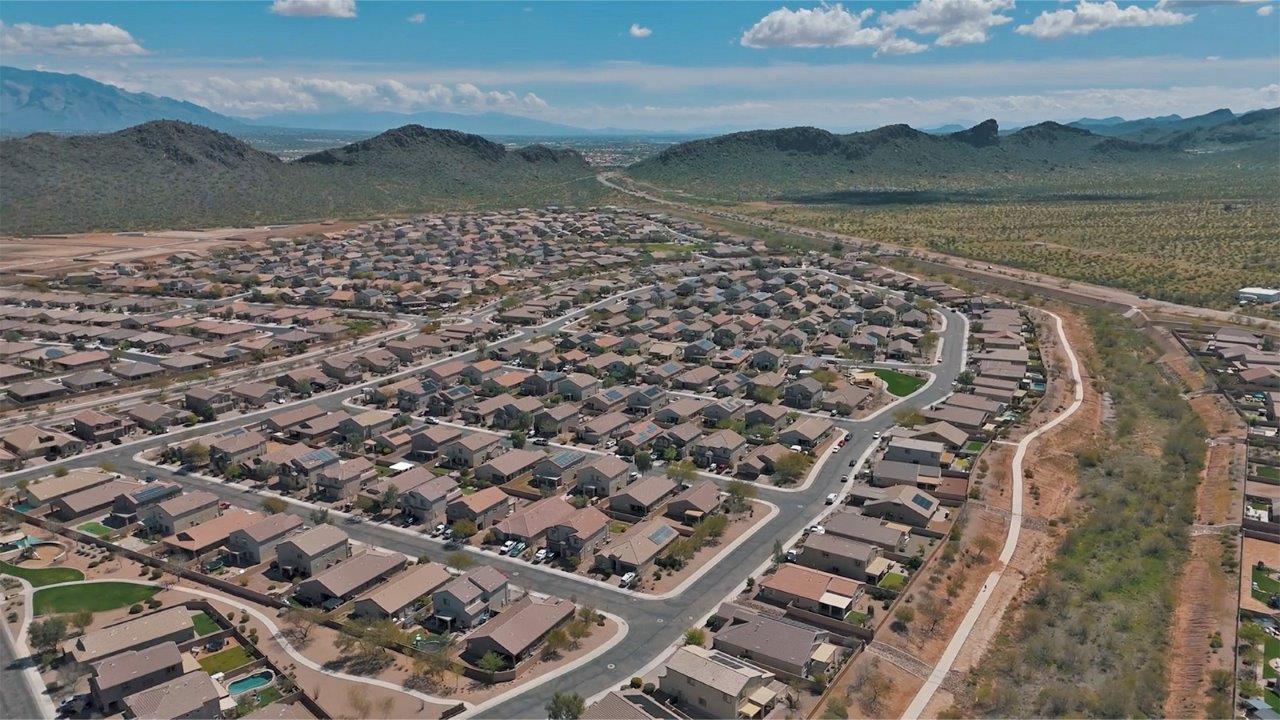 Welcome to The Pearl, a beautifully designed single-story new home located in the serene Cholla Ridge neighborhood of Saguaro Bloom. Spanning 2,431 square feet, this home offers four spacious bedrooms and three full bathrooms, making it an ideal choice for families who value both space and comfort.  As you enter through the front porch, you’re welcomed into a bright and open entryway that leads to the heart of the home. The expansive great room, dining area, and kitchen are seamlessly connected, providing a perfect setting for both everyday living and entertaining. The kitchen is a chef’s delight, featuring a large island, granite countertops, and Shaker-style cabinetry in double espresso. With a generously sized pantry and modern stainless steel gas appliances, this kitchen is both functional and stylish.  The Pearl’s layout includes a well-placed primary bedroom at the rear of the home, ensuring privacy and tranquility. The primary suite features a spacious walk-in closet and an en-suite bathroom with dual executive-height vanities and a large walk-in shower. The additional three bedrooms are located towards the front and sides of the home, each offering ample closet space and access to two full bathrooms, making this layout perfect for families and guests alike.  The outdoor living space is just as inviting, with a covered patio that extends from the great room, providing an ideal spot for enjoying Arizona’s beautiful weather. Whether you’re hosting a gathering or simply relaxing with a good book, this space is designed for your enjoyment.  The Pearl also features a dedicated utility room near the kitchen, making household tasks more convenient. A two-car garage offers plenty of space for vehicles and additional storage.  Built with energy efficiency and modern living in mind, The Pearl incorporates eco-friendly features and smart home technology, ensuring a comfortable and sustainable lifestyle. Large windows throughout the home allow natural light to flood the space, creating a warm and inviting atmosphere.  Located within the exclusive Cholla Ridge neighborhood at Saguaro Bloom, residents of The Pearl enjoy a range of amenities, including beautiful 12x24” tile flooring, and gourmet kitchens in select homes, all on lots with no rear neighbors. The community offers access to two pools, walking trails, and parks, all set against the stunning backdrop of the Tucson Mountains.  The Pearl combines style, comfort, and practicality, making it a perfect place to call home in one of Marana’s most sought-after communities.