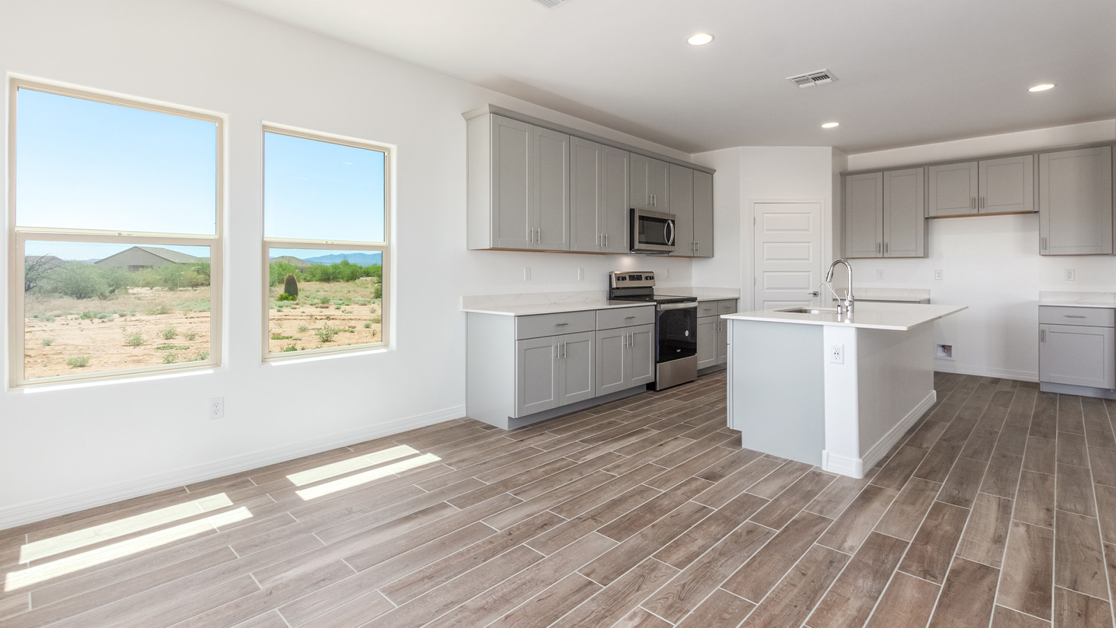 Introducing The Catalina, an expansive single-story home set in the serene and spacious Sahuarita Acres community. Covering 2,392 square feet, this residence offers four bedrooms and three bathrooms, perfectly balancing space and functionality for modern family living.  As you step into The Catalina, the entryway opens up to reveal a generous dining room that leads directly into the heart of the home—the great room. This central living space is designed for both relaxation and entertainment, with large windows that invite abundant natural light. The adjoining kitchen, complete with a large island, quartz countertops, and 42” upper cabinets, is as practical as it is stylish. A walk-in pantry provides ample storage, ensuring that everything you need is at your fingertips.  The primary bedroom, located in its own private wing, features a spacious walk-in closet and an en-suite bathroom equipped with dual sinks and a luxurious shower, offering a perfect space for winding down after a busy day. The additional three bedrooms are well-spaced throughout the home, each offering easy access to one of the two additional bathrooms, making it ideal for family living or hosting guests.  One of the standout features of The Catalina is its seamless blend of indoor and outdoor living. The covered patio, accessible from the great room, is an ideal spot for outdoor dining or simply enjoying the expansive one-acre lot that comes with each home in Sahuarita Acres. Whether you envision a garden, a play area, or even a pool, the possibilities are endless with the amount of outdoor space available.  The Catalina also includes a three-car garage and ample driveway space, perfect for parking vehicles, RVs, or additional storage. With D.R. Horton’s Home is Connected® Smart Home package, this home ensures you stay connected and secure, featuring a smart thermostat, video doorbell, keyless entry, a Wi-Fi-enabled garage door opener, and more.  Built with energy efficiency in mind, The Catalina features spray foam insulation and meets DOE Zero Energy Ready Home standards, helping you save on energy costs while contributing to a greener environment.  Nestled in the tranquil Sahuarita Acres community, residents enjoy the best of both worlds—peaceful, spacious living with easy access to urban amenities and outdoor recreation. With its combination of modern conveniences, thoughtful design, and expansive lots, The Catalina offers a lifestyle that truly captures the essence of Arizona living.