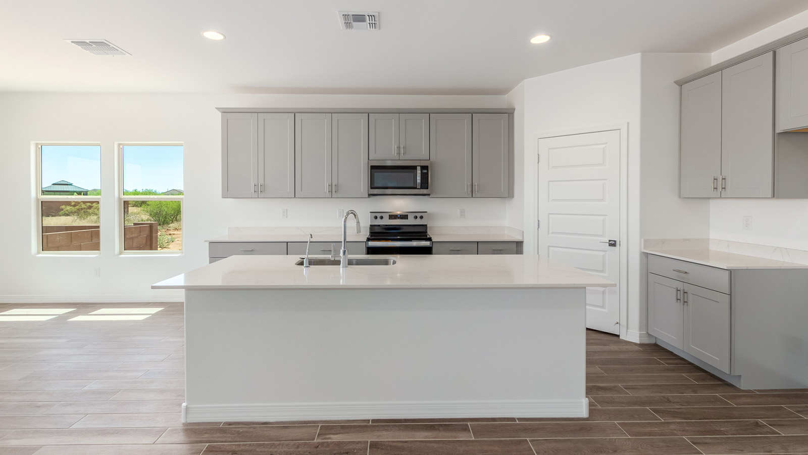 Introducing The Catalina, an expansive single-story home set in the serene and spacious Sahuarita Acres community. Covering 2,392 square feet, this residence offers four bedrooms and three bathrooms, perfectly balancing space and functionality for modern family living.  As you step into The Catalina, the entryway opens up to reveal a generous dining room that leads directly into the heart of the home—the great room. This central living space is designed for both relaxation and entertainment, with large windows that invite abundant natural light. The adjoining kitchen, complete with a large island, quartz countertops, and 42” upper cabinets, is as practical as it is stylish. A walk-in pantry provides ample storage, ensuring that everything you need is at your fingertips.  The primary bedroom, located in its own private wing, features a spacious walk-in closet and an en-suite bathroom equipped with dual sinks and a luxurious shower, offering a perfect space for winding down after a busy day. The additional three bedrooms are well-spaced throughout the home, each offering easy access to one of the two additional bathrooms, making it ideal for family living or hosting guests.  One of the standout features of The Catalina is its seamless blend of indoor and outdoor living. The covered patio, accessible from the great room, is an ideal spot for outdoor dining or simply enjoying the expansive one-acre lot that comes with each home in Sahuarita Acres. Whether you envision a garden, a play area, or even a pool, the possibilities are endless with the amount of outdoor space available.  The Catalina also includes a three-car garage and ample driveway space, perfect for parking vehicles, RVs, or additional storage. With D.R. Horton’s Home is Connected® Smart Home package, this home ensures you stay connected and secure, featuring a smart thermostat, video doorbell, keyless entry, a Wi-Fi-enabled garage door opener, and more.  Built with energy efficiency in mind, The Catalina features spray foam insulation and meets DOE Zero Energy Ready Home standards, helping you save on energy costs while contributing to a greener environment.  Nestled in the tranquil Sahuarita Acres community, residents enjoy the best of both worlds—peaceful, spacious living with easy access to urban amenities and outdoor recreation. With its combination of modern conveniences, thoughtful design, and expansive lots, The Catalina offers a lifestyle that truly captures the essence of Arizona living.