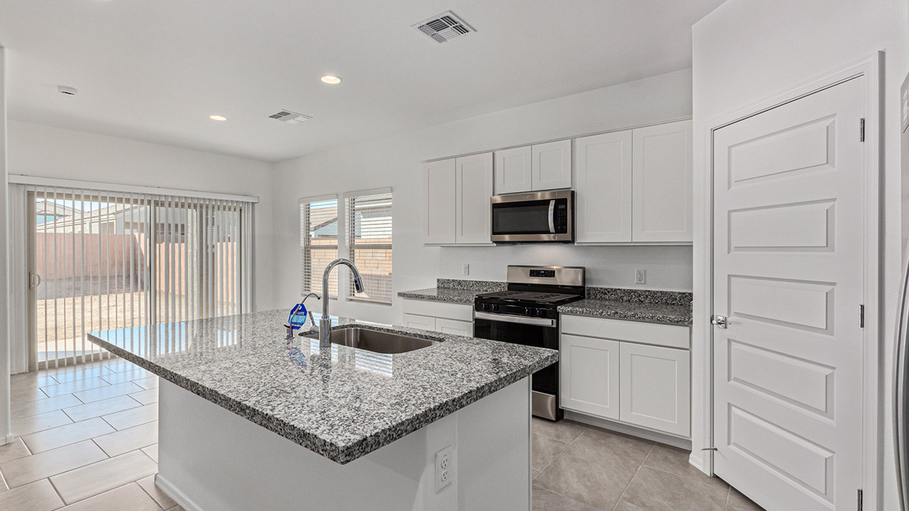 Explore The Baxter at The Oasis at Rocking K in Vail, Arizona, a meticulously designed single-story new home floorplan offering 1,423 square feet of beautifully appointed living space.  As you step inside, you'll immediately appreciate the open and inviting layout that seamlessly connects the great room, dining area, and kitchen. The heart of the home, the kitchen, is equipped with sleek stainless-steel appliances, including a built-in microwave and gas range. The central island with a breakfast bar serves as a gathering spot for casual meals and entertaining.  The adjacent dining room flows effortlessly into a covered patio, perfect for extending your living space outdoors. The great room, with its large windows, allows natural light to flood the space, creating a warm and welcoming atmosphere.  The primary suite is a private hideaway, featuring a spacious walk-in closet and an en-suite bathroom. Two additional bedrooms are located near the front of the home, offering ample space and privacy for family members or guests. These rooms share a well-appointed full bathroom.  Additional standard features of The Baxter include energy-efficient dual-pane windows, a tankless water heater, and smart home technology that allows you to control the thermostat, lighting, and security system from your smartphone. The home also comes with a fully landscaped front yard with automatic drip irrigation, ensuring your home looks beautiful with minimal effort.  The two-car garage, utility room with washer/dryer hookups, and abundant storage throughout the home make the Baxter not only stylish but incredibly functional, catering to the needs of modern living.  The Baxter at The Oasis at Rocking K is where thoughtful design meets convenience, making it the perfect home for those seeking a blend of comfort, style, and functionality.