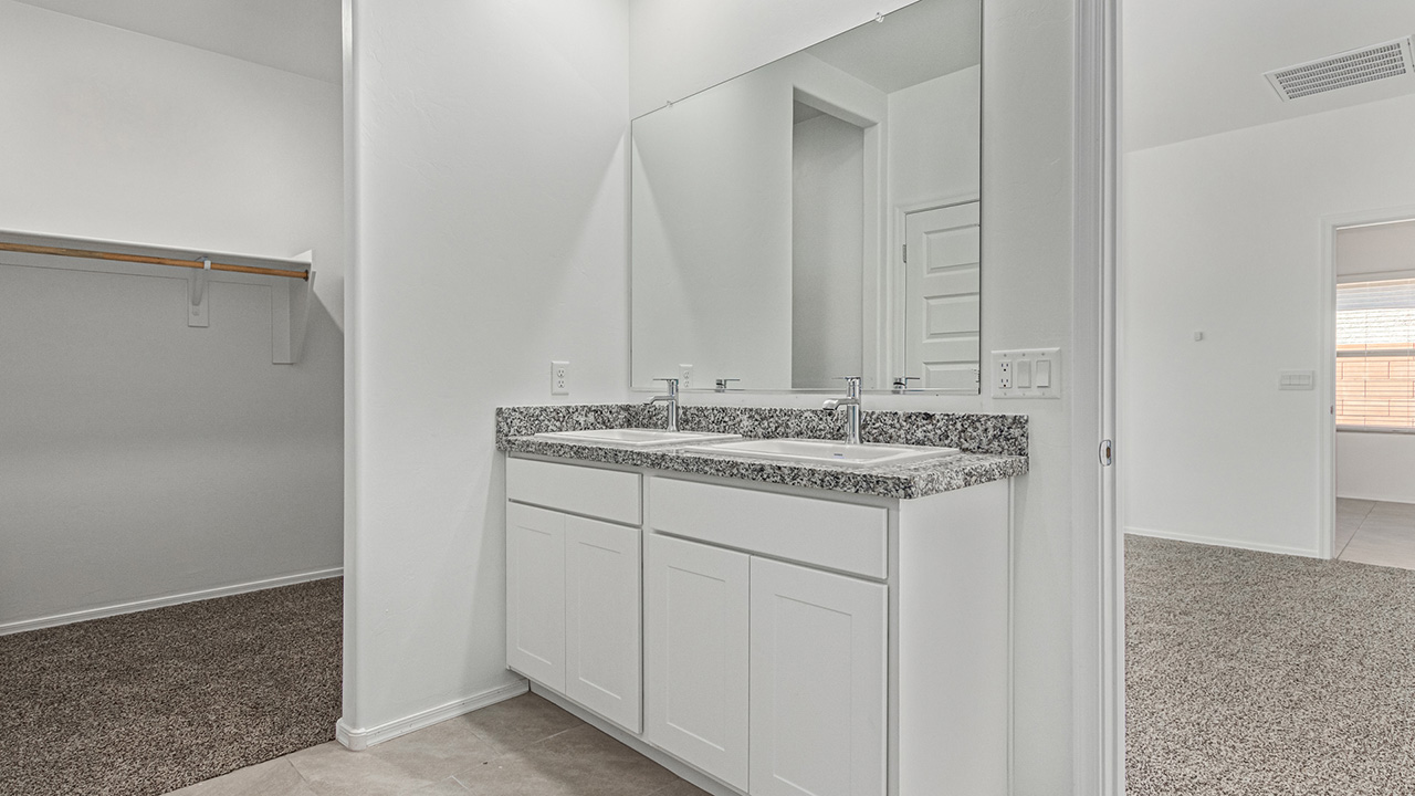 Explore The Baxter at The Oasis at Rocking K in Vail, Arizona, a meticulously designed single-story new home floorplan offering 1,423 square feet of beautifully appointed living space.  As you step inside, you'll immediately appreciate the open and inviting layout that seamlessly connects the great room, dining area, and kitchen. The heart of the home, the kitchen, is equipped with sleek stainless-steel appliances, including a built-in microwave and gas range. The central island with a breakfast bar serves as a gathering spot for casual meals and entertaining.  The adjacent dining room flows effortlessly into a covered patio, perfect for extending your living space outdoors. The great room, with its large windows, allows natural light to flood the space, creating a warm and welcoming atmosphere.  The primary suite is a private hideaway, featuring a spacious walk-in closet and an en-suite bathroom. Two additional bedrooms are located near the front of the home, offering ample space and privacy for family members or guests. These rooms share a well-appointed full bathroom.  Additional standard features of The Baxter include energy-efficient dual-pane windows, a tankless water heater, and smart home technology that allows you to control the thermostat, lighting, and security system from your smartphone. The home also comes with a fully landscaped front yard with automatic drip irrigation, ensuring your home looks beautiful with minimal effort.  The two-car garage, utility room with washer/dryer hookups, and abundant storage throughout the home make the Baxter not only stylish but incredibly functional, catering to the needs of modern living.  The Baxter at The Oasis at Rocking K is where thoughtful design meets convenience, making it the perfect home for those seeking a blend of comfort, style, and functionality.