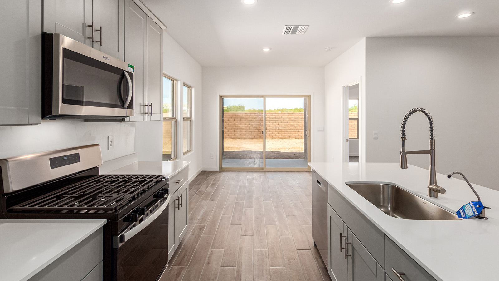 Explore The Baxter at The Oasis at Rocking K in Vail, Arizona, a meticulously designed single-story new home floorplan offering 1,423 square feet of beautifully appointed living space.  As you step inside, you'll immediately appreciate the open and inviting layout that seamlessly connects the great room, dining area, and kitchen. The heart of the home, the kitchen, is equipped with sleek stainless-steel appliances, including a built-in microwave and gas range. The central island with a breakfast bar serves as a gathering spot for casual meals and entertaining.  The adjacent dining room flows effortlessly into a covered patio, perfect for extending your living space outdoors. The great room, with its large windows, allows natural light to flood the space, creating a warm and welcoming atmosphere.  The primary suite is a private hideaway, featuring a spacious walk-in closet and an en-suite bathroom. Two additional bedrooms are located near the front of the home, offering ample space and privacy for family members or guests. These rooms share a well-appointed full bathroom.  Additional standard features of The Baxter include energy-efficient dual-pane windows, a tankless water heater, and smart home technology that allows you to control the thermostat, lighting, and security system from your smartphone. The home also comes with a fully landscaped front yard with automatic drip irrigation, ensuring your home looks beautiful with minimal effort.  The two-car garage, utility room with washer/dryer hookups, and abundant storage throughout the home make the Baxter not only stylish but incredibly functional, catering to the needs of modern living.  The Baxter at The Oasis at Rocking K is where thoughtful design meets convenience, making it the perfect home for those seeking a blend of comfort, style, and functionality.