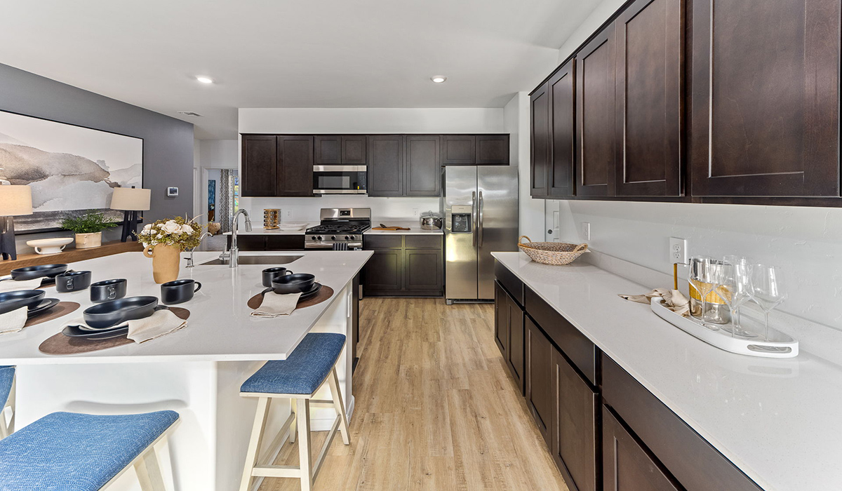 Step into The Kingston at Barnett Village, Marana, Arizona – a perfect blend of comfort, modern living, and energy efficiency. This thoughtfully crafted one-story home spans 2,068 square feet and offers four bedrooms and two bathrooms, ideal for families of all sizes.  The open-concept design features a spacious great room that effortlessly connects with the kitchen and dining area, creating an inviting central hub for everyday living and entertaining. The kitchen is equipped with contemporary appliances and a pantry, offering ample storage and convenience for meal preparation.  The primary bedroom, located at the rear of the home, provides a peaceful retreat with a private ensuite bathroom and a generous walk-in closet. The additional three bedrooms are positioned at the front of the house, offering versatility for use as guest rooms, a home office, or children’s bedrooms. Step outside to the covered patio, a perfect spot to enjoy the beautiful Arizona weather, whether for morning coffee or evening relaxation.  The Kingston also boasts a covered patio, perfect for enjoying Arizona’s beautiful desert evenings. Whether it’s morning coffee or evening relaxation, this outdoor space extends your living area into the serene landscape of Barnett Village.  Built with energy efficiency as a priority, the Kingston includes smart home technology, which not only simplifies daily living but also helps reduce utility costs. A two-car garage provides ample parking and additional storage space, enhancing the home’s functionality.  Images shown are for reference only. They depict the sales model home and may not represent the actual home.