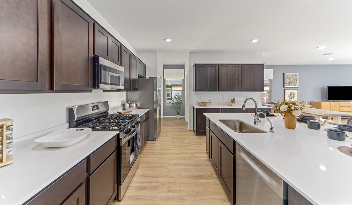 Step into The Kingston at Barnett Village, Marana, Arizona – a perfect blend of comfort, modern living, and energy efficiency. This thoughtfully crafted one-story home spans 2,068 square feet and offers four bedrooms and two bathrooms, ideal for families of all sizes.  The open-concept design features a spacious great room that effortlessly connects with the kitchen and dining area, creating an inviting central hub for everyday living and entertaining. The kitchen is equipped with contemporary appliances and a pantry, offering ample storage and convenience for meal preparation.  The primary bedroom, located at the rear of the home, provides a peaceful retreat with a private ensuite bathroom and a generous walk-in closet. The additional three bedrooms are positioned at the front of the house, offering versatility for use as guest rooms, a home office, or children’s bedrooms. Step outside to the covered patio, a perfect spot to enjoy the beautiful Arizona weather, whether for morning coffee or evening relaxation.  The Kingston also boasts a covered patio, perfect for enjoying Arizona’s beautiful desert evenings. Whether it’s morning coffee or evening relaxation, this outdoor space extends your living area into the serene landscape of Barnett Village.  Built with energy efficiency as a priority, the Kingston includes smart home technology, which not only simplifies daily living but also helps reduce utility costs. A two-car garage provides ample parking and additional storage space, enhancing the home’s functionality.  Images shown are for reference only. They depict the sales model home and may not represent the actual home.